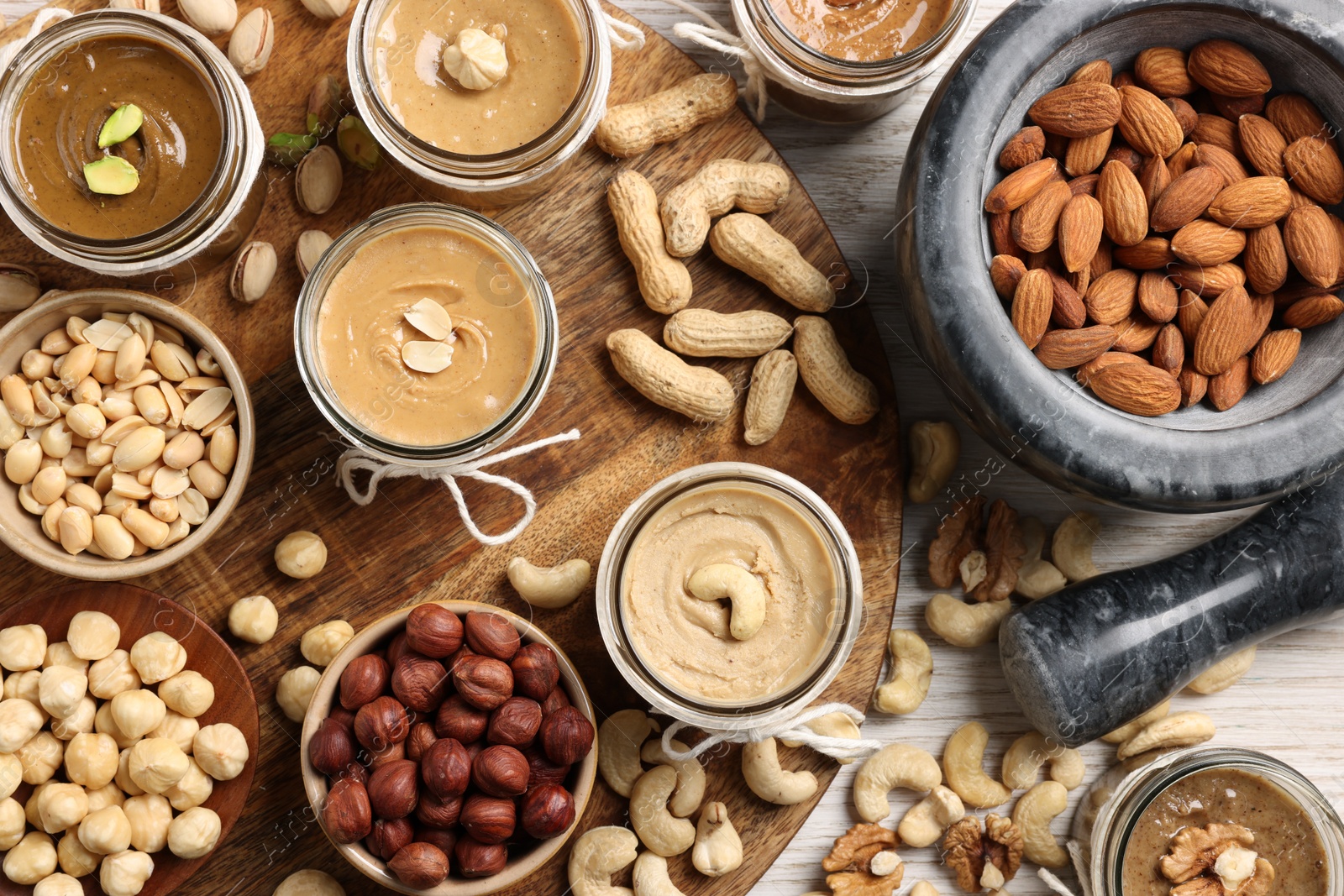 Photo of Making nut butters from different nuts, flat lay composition on wooden table