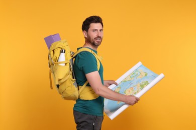 Photo of Happy man with backpack and map on orange background. Active tourism