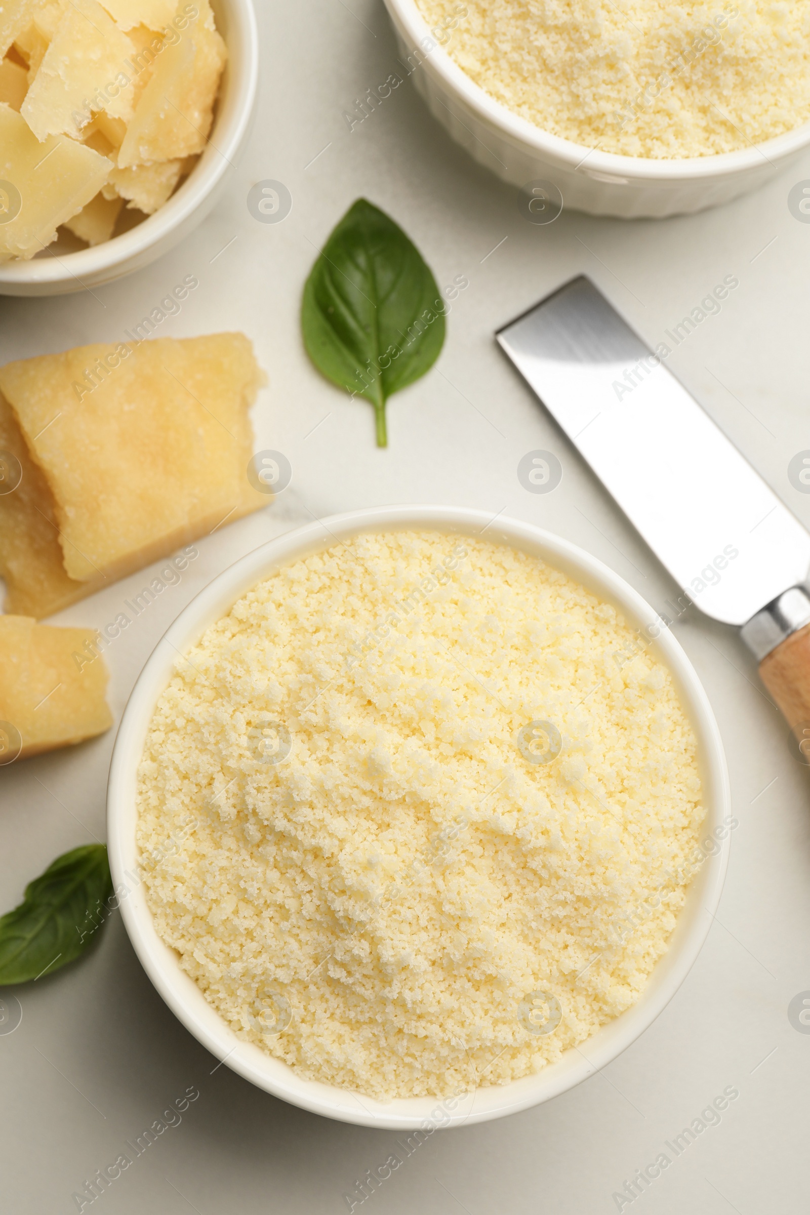 Photo of Bowl with grated parmesan cheese on white table, flat lay