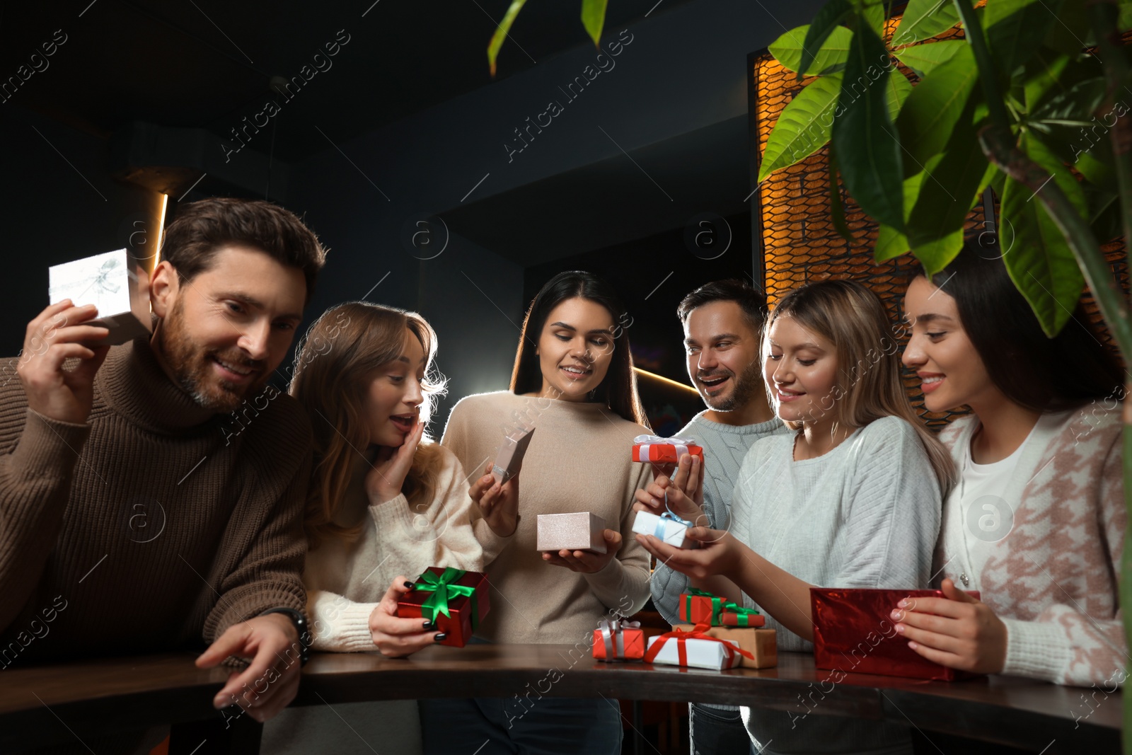 Photo of Friends exchanging gifts at table in cafe