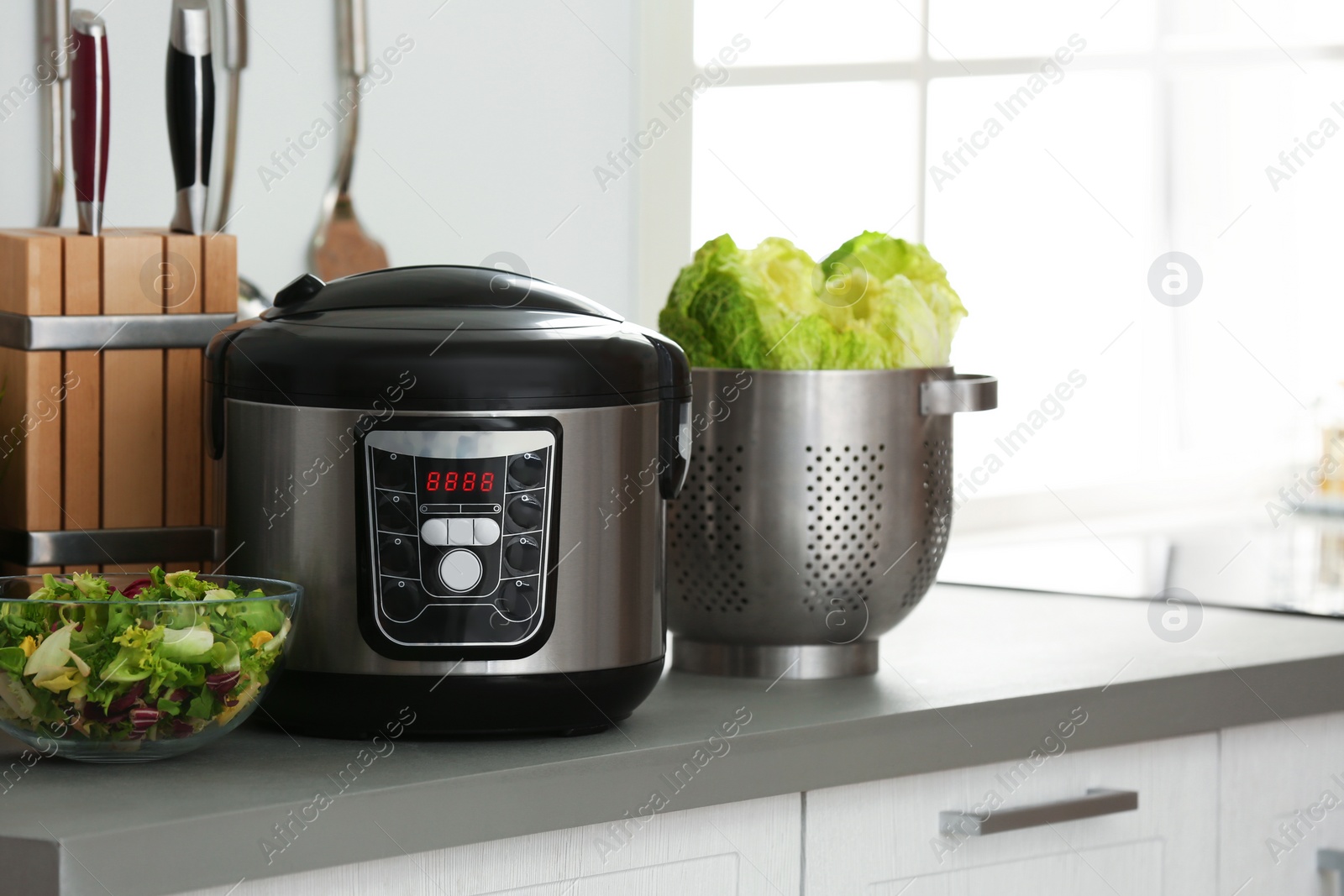 Photo of Modern electric multi cooker and food on kitchen countertop. Space for text