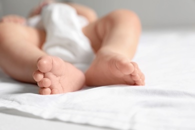 Photo of Little baby lying on bed sheet against light background, closeup. Space for text