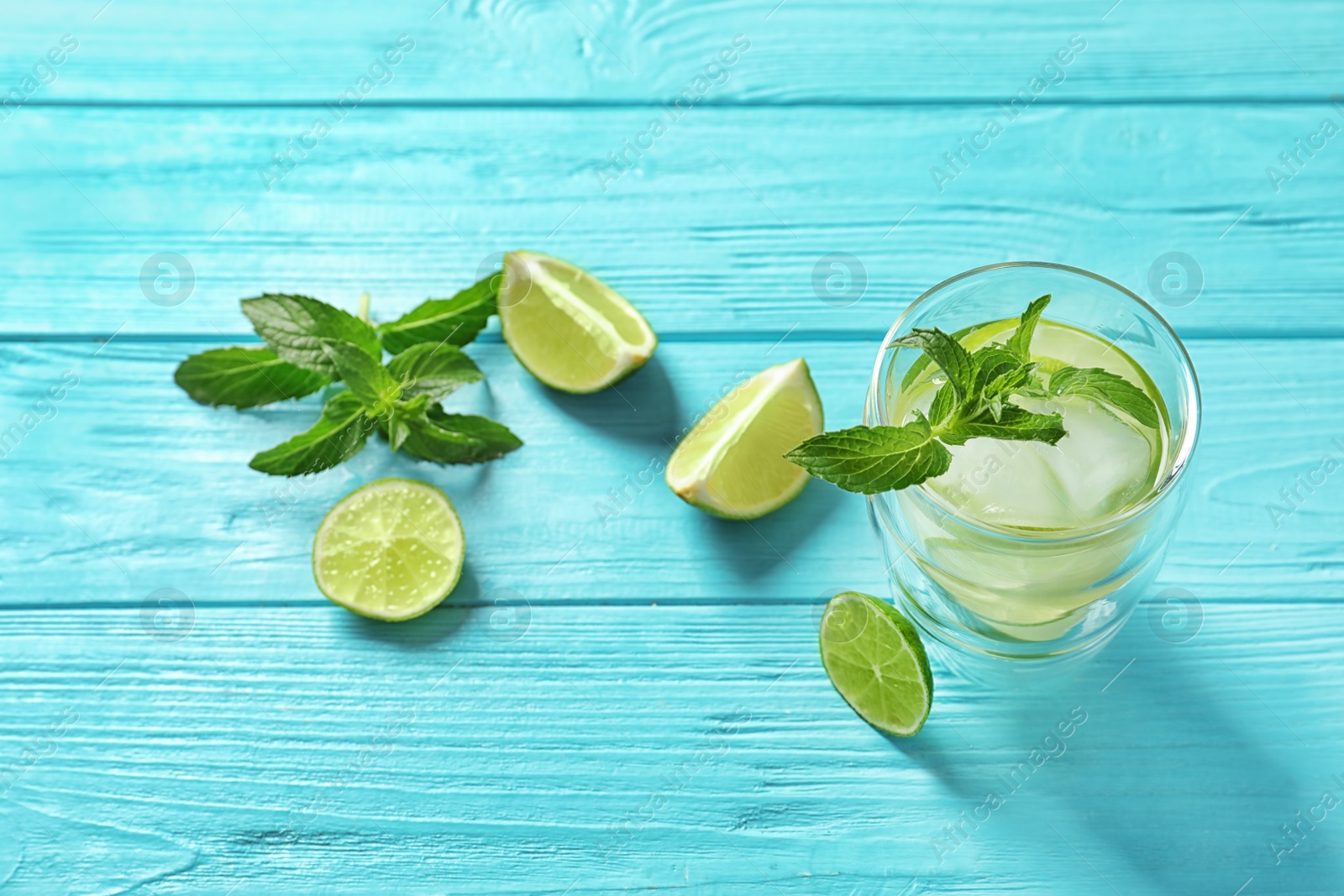 Photo of Natural lemonade with lime and mint in glass on wooden table