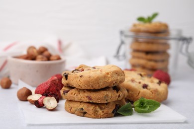 Photo of Cookies with freeze dried fruits, nuts and mint on white table, closeup. Space for text