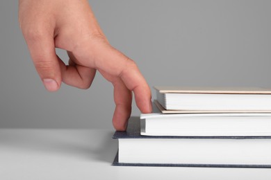 Photo of Woman imitating stepping up on books with her fingers against grey background, closeup
