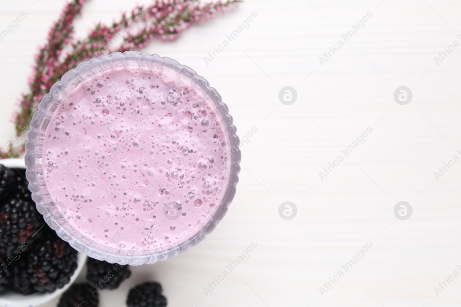 Photo of Delicious blackberry smoothie in glass on white wooden table, flat lay. Space for text