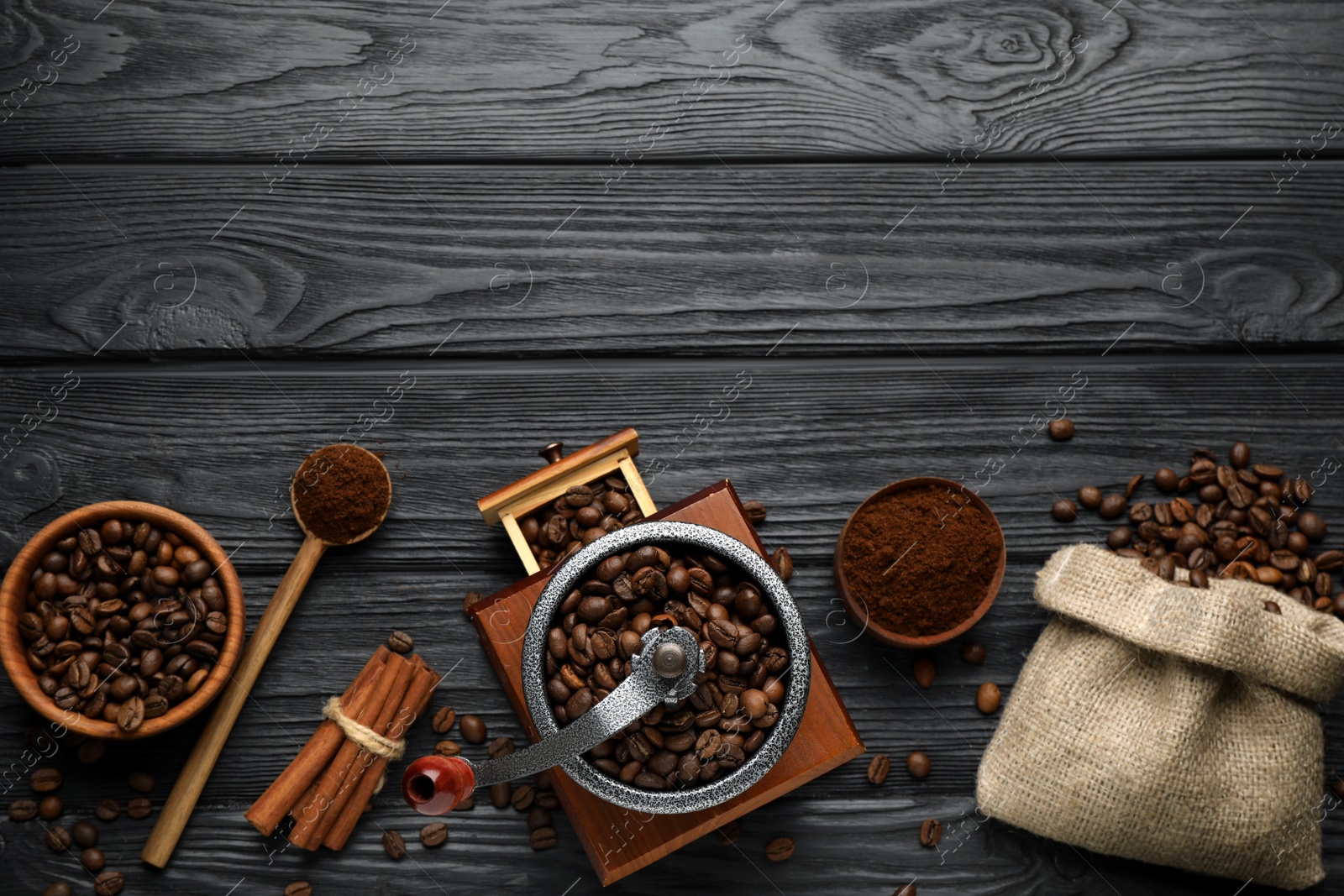 Photo of Vintage manual coffee grinder, powder and beans on black wooden table, flat lay. Space for text