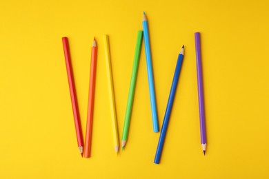 Photo of Colorful wooden pencils on yellow background, flat lay