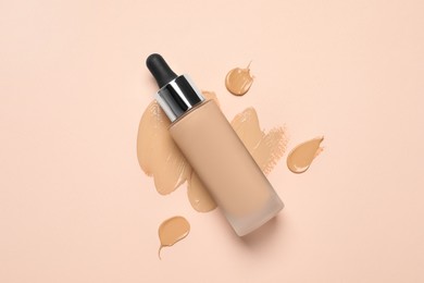 Photo of Liquid foundation and swatches on beige background, top view