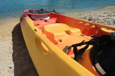 Photo of Bright kayak on sand near river, closeup