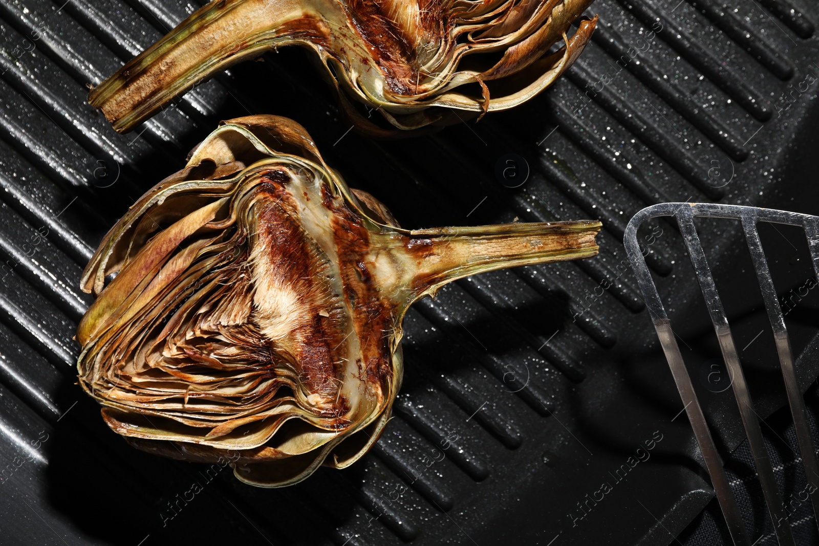 Photo of Pan with tasty grilled artichokes, closeup view