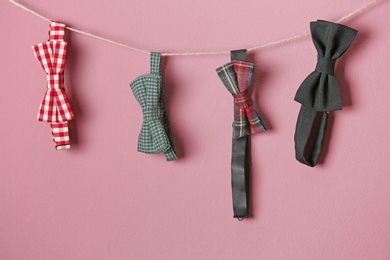 Bow ties hanging on rope against color background