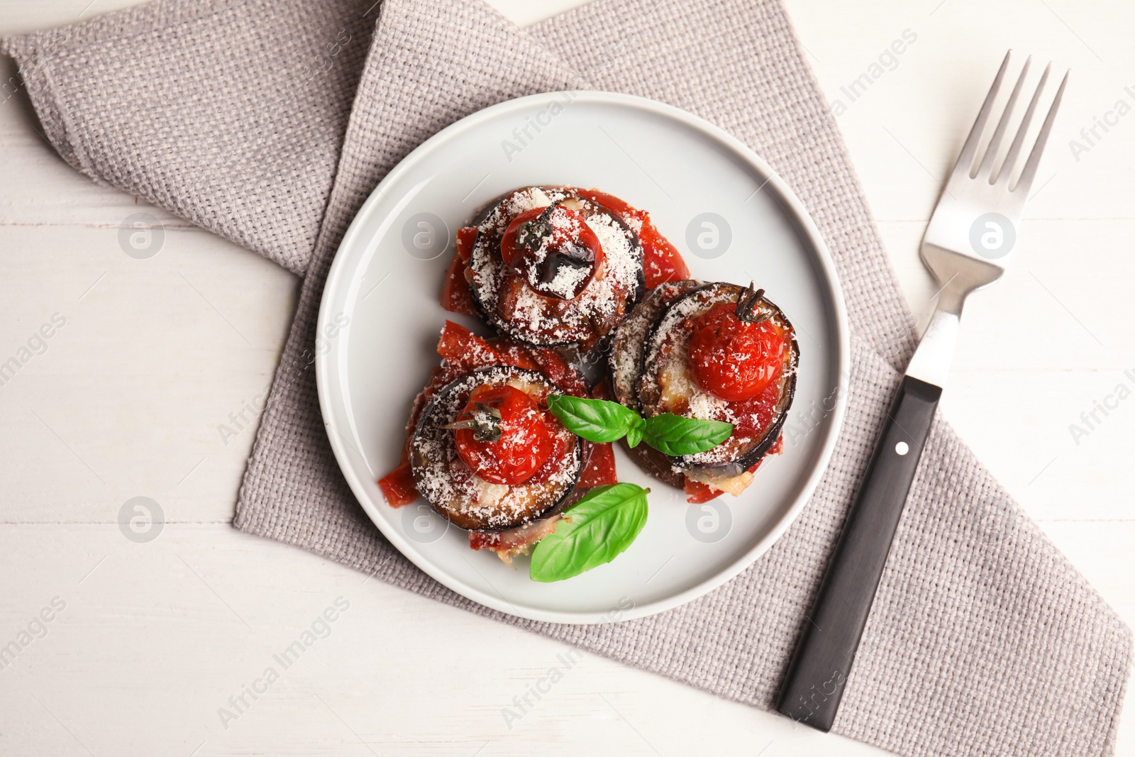 Photo of Baked eggplant with tomatoes, cheese and basil served on white wooden table, flat lay