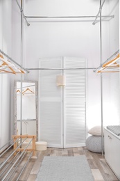 Photo of Empty modern dressing room with racks and hangers