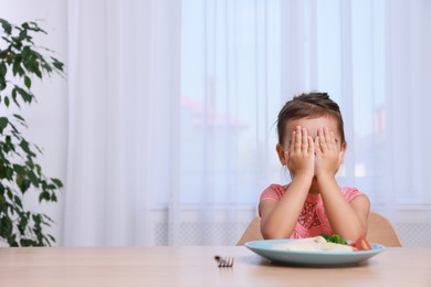 Photo of Cute little girl crying and refusing to eat her breakfast at home, space for text