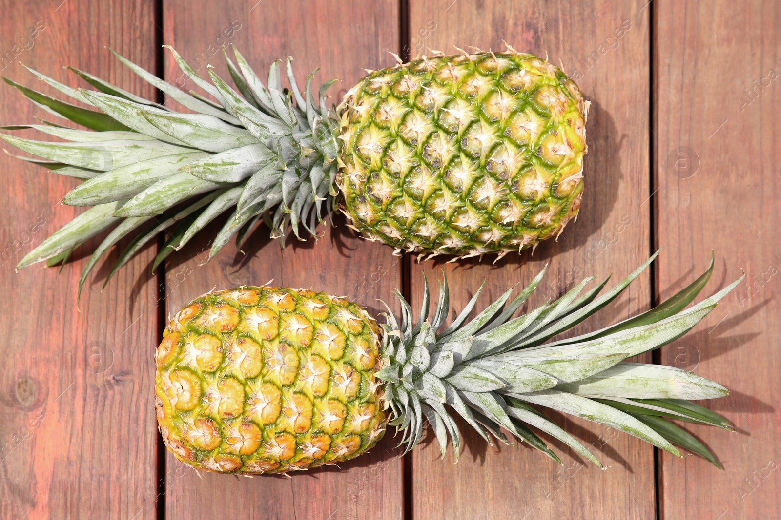 Photo of Delicious ripe pineapples on wooden table. Exotic fruit