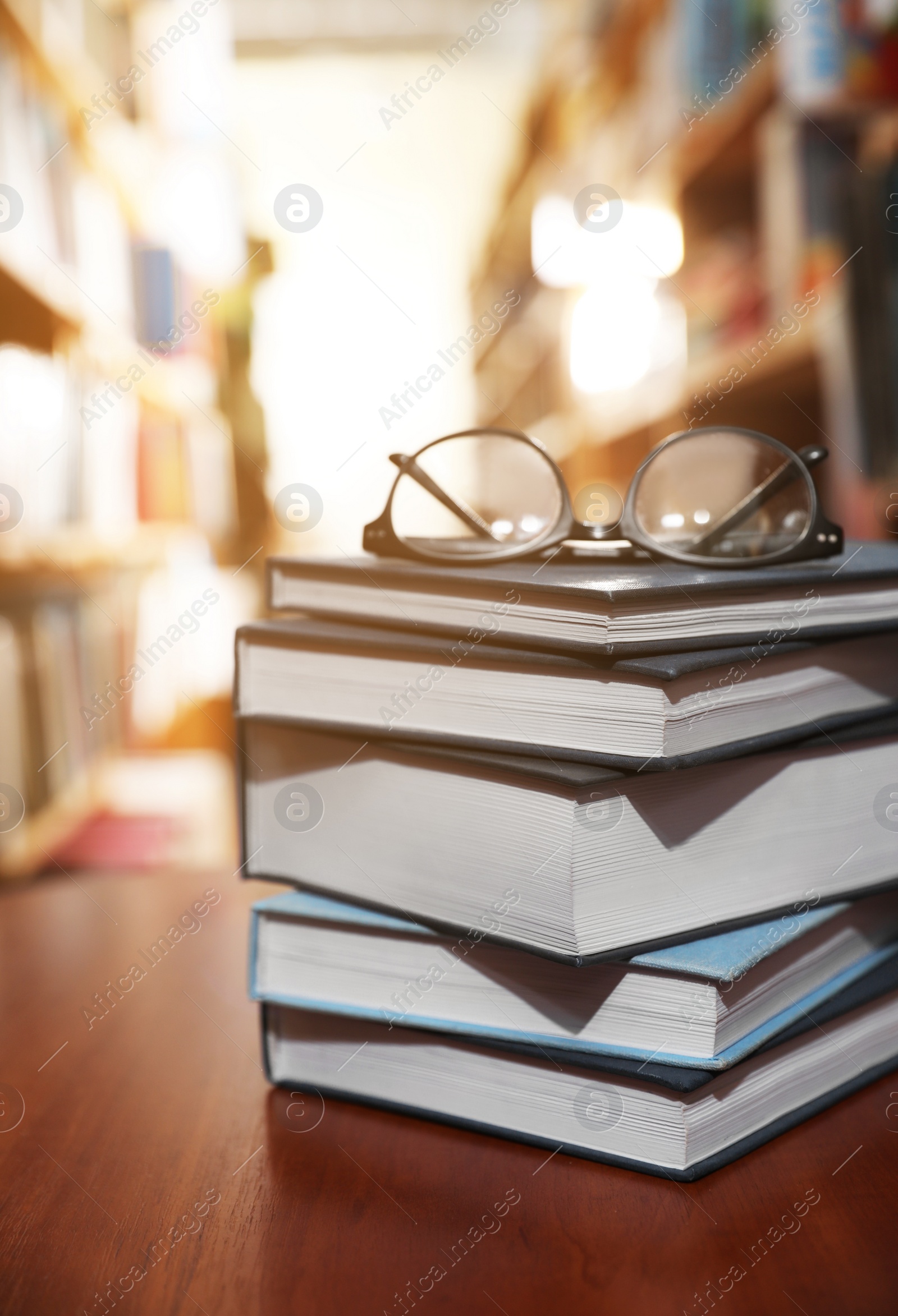 Photo of Stack of books and glasses on table in library