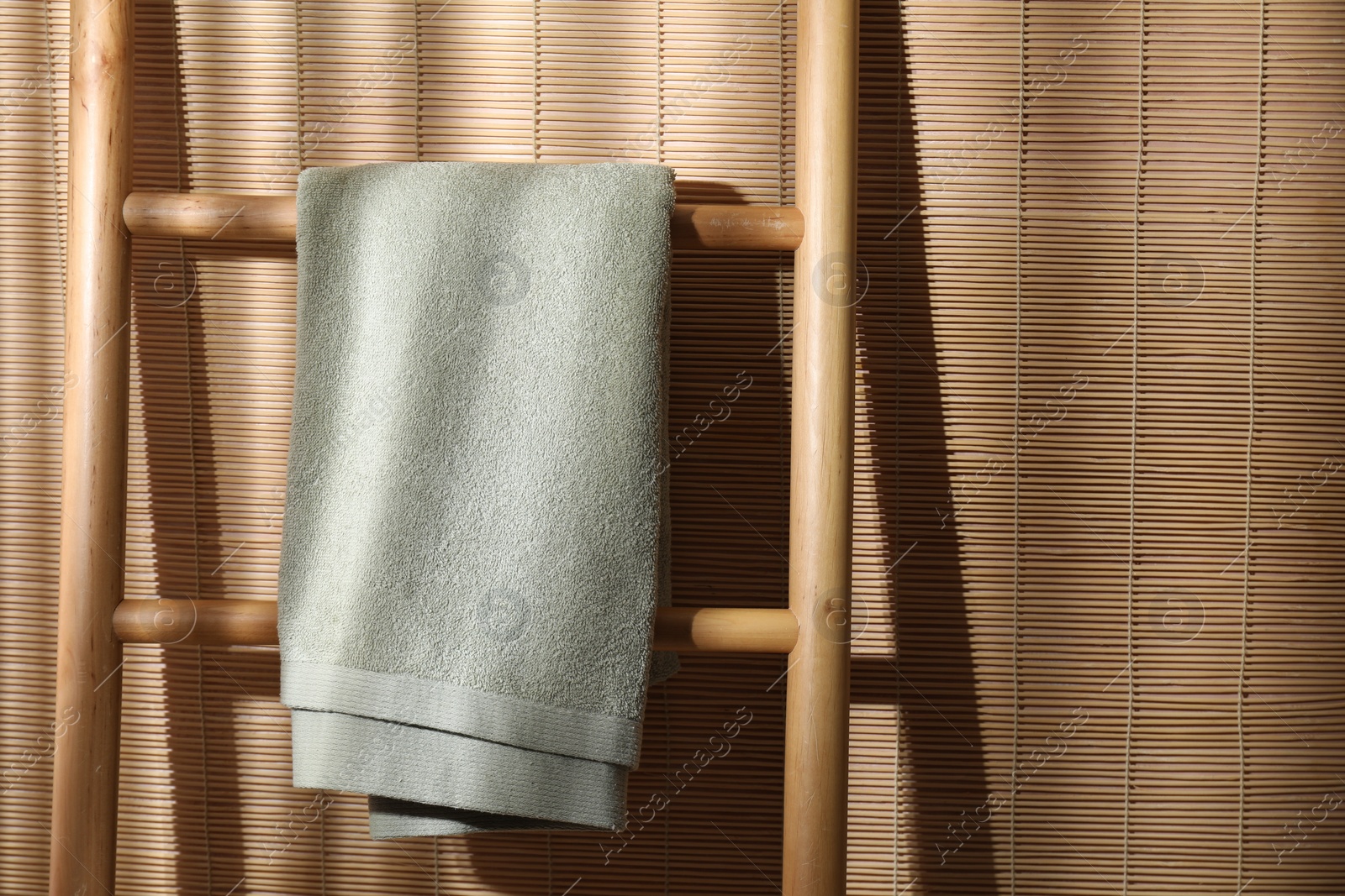 Photo of Green terry towel on wooden ladder indoors, space for text