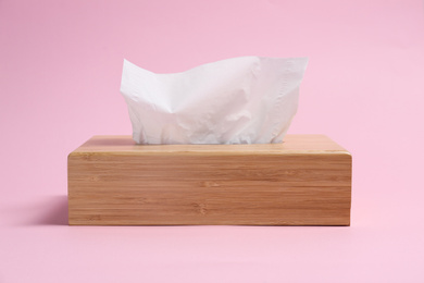 Photo of Wooden holder with paper tissues on pink background