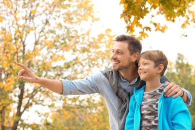 Photo of Father and his son spending time together in park. Autumn walk