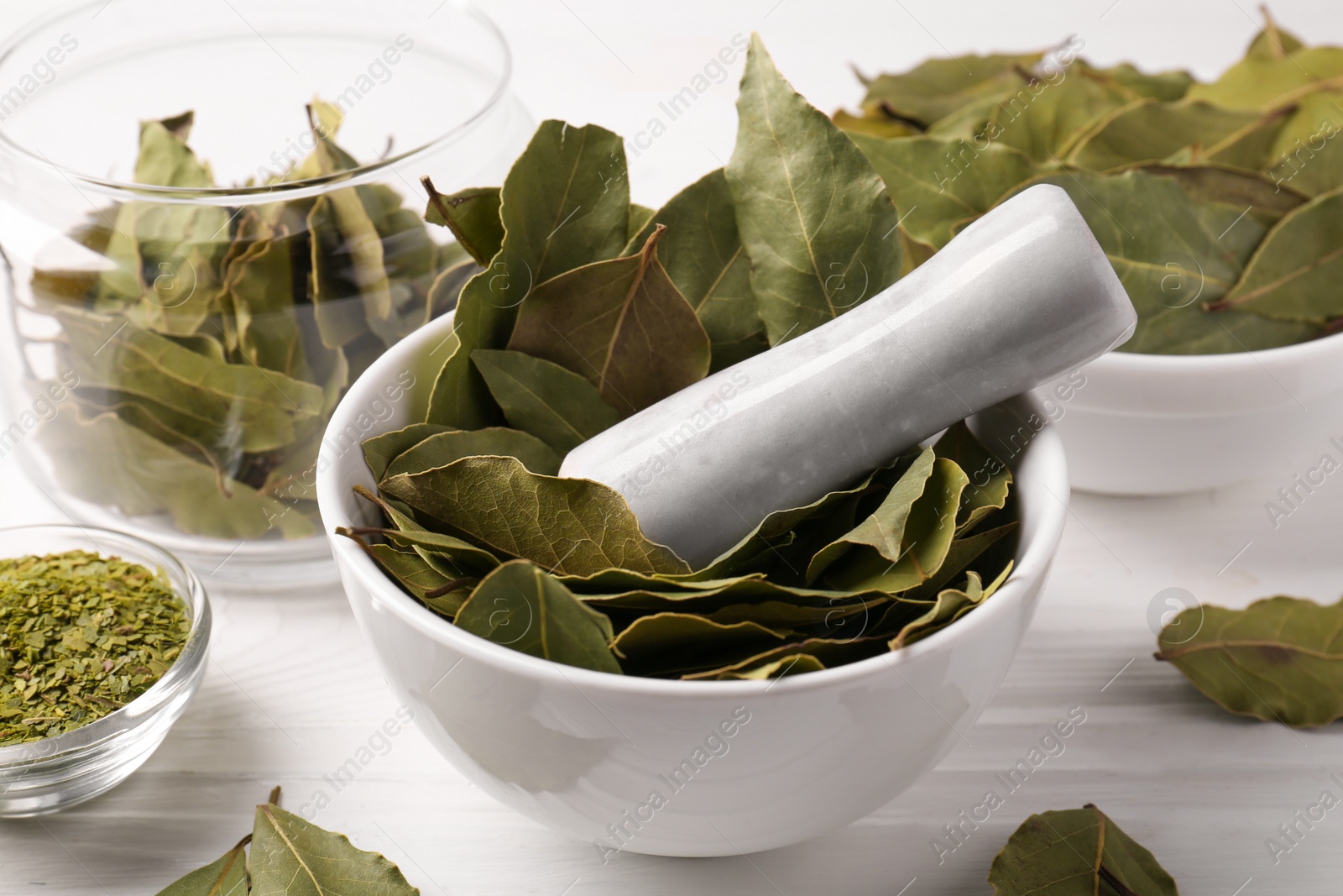 Photo of Whole and ground bay leaves on white wooden table, closeup