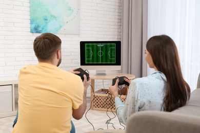 Photo of Happy young couple playing video games at home