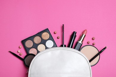 Photo of Cosmetic bag with makeup products and accessories on pink background, flat lay. Space for text