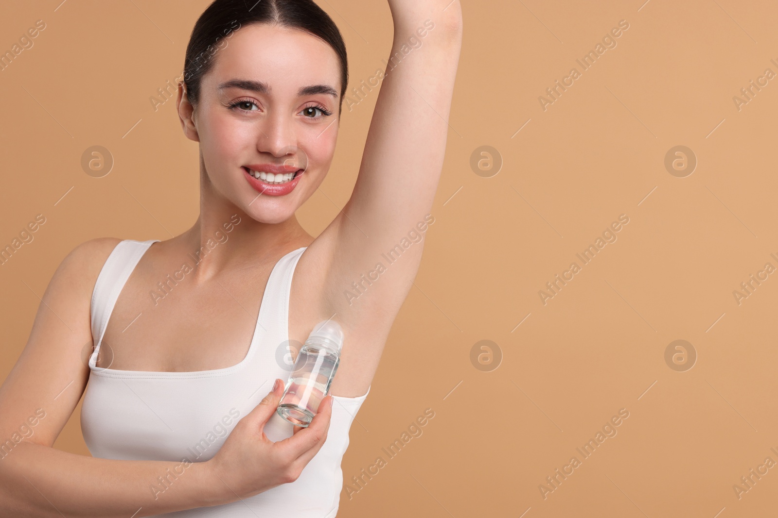 Photo of Beautiful woman applying deodorant on beige background, space for text