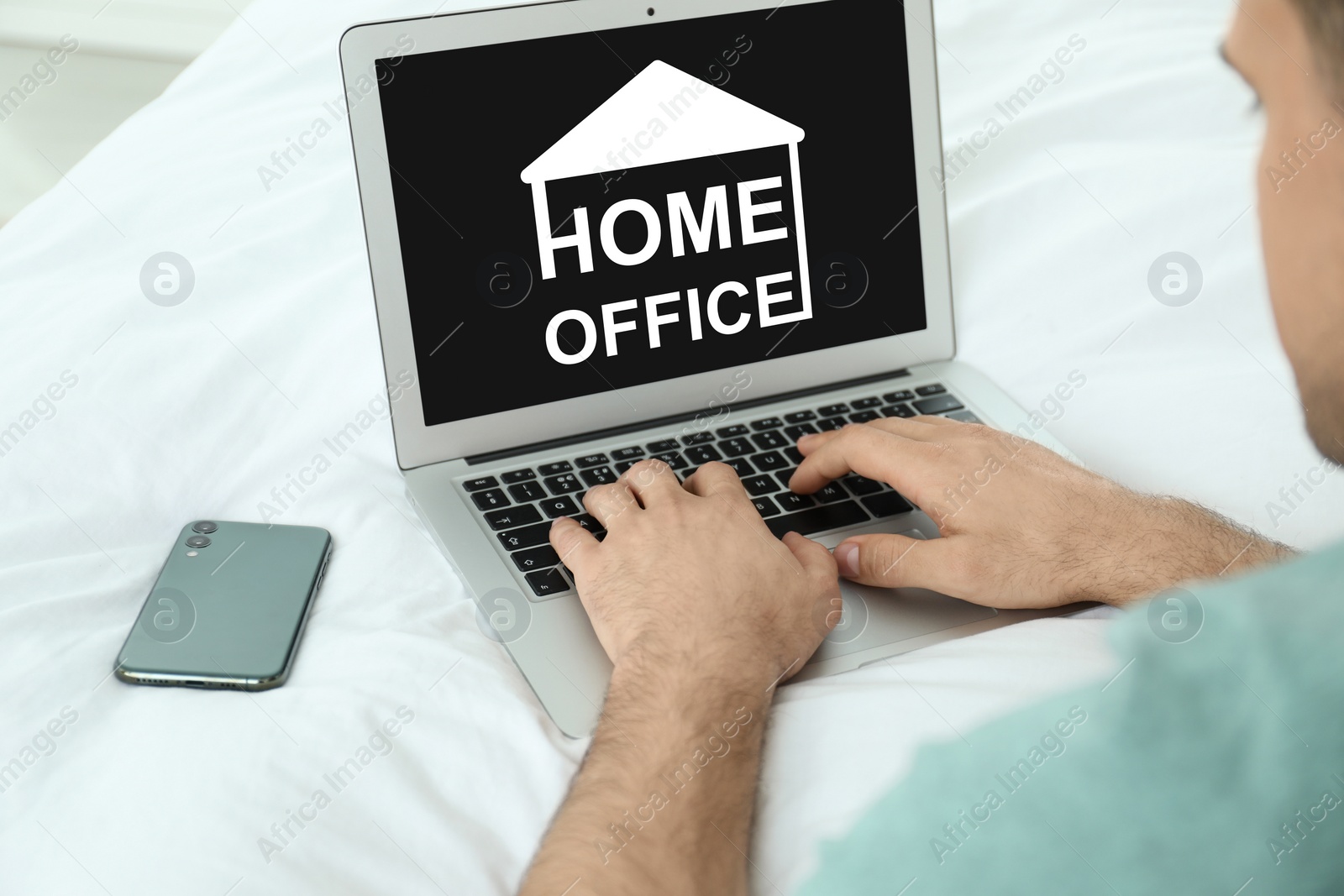 Image of Man working with modern laptop on bed, closeup. Home office