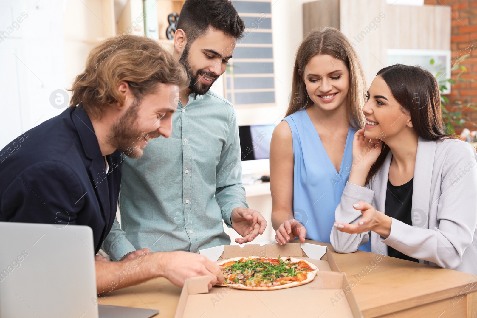 Photo of Office employees having pizza for lunch at workplace. Food delivery