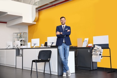 Salesman standing in modern auto dealership. Buying new car