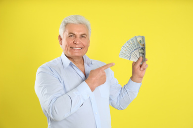 Photo of Happy senior man with cash money on yellow background