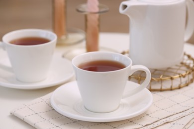 Photo of Cups of tea and teapot on white table