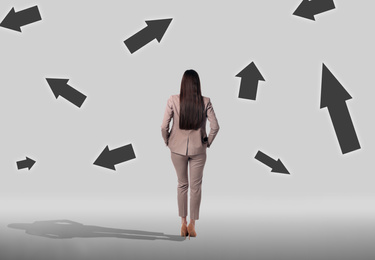 Image of Choose your way. Woman and arrows pointing in different directions on light background, back view