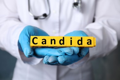 Image of Doctor holding yellow cubes with word Candida, closeup