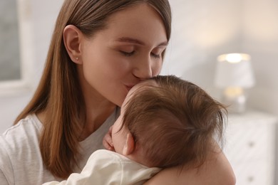 Photo of Happy mother kissing her little baby at home, closeup