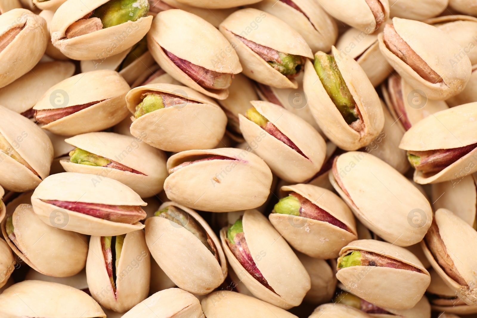 Photo of Tasty unpeeled pistachios as background, top view