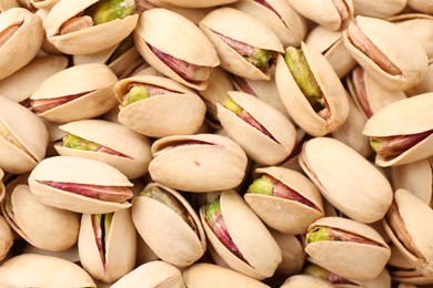 Photo of Tasty unpeeled pistachios as background, top view