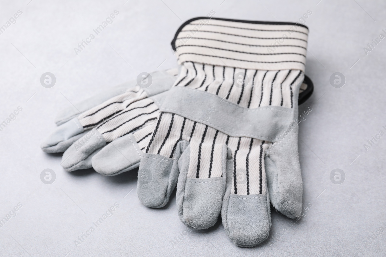 Photo of Pair of color gardening gloves on light grey table, closeup