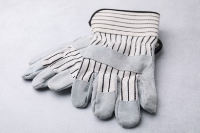 Pair of color gardening gloves on light grey table, closeup