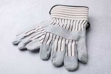 Photo of Pair of color gardening gloves on light grey table, closeup