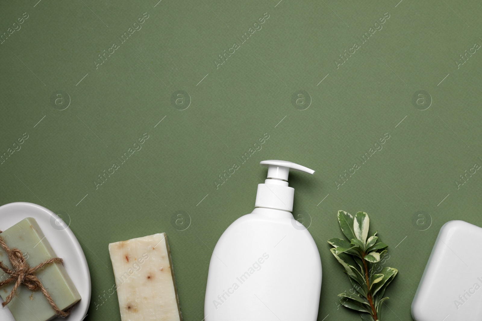 Photo of Soap bars and bottle dispenser on green background, flat lay. Space for text