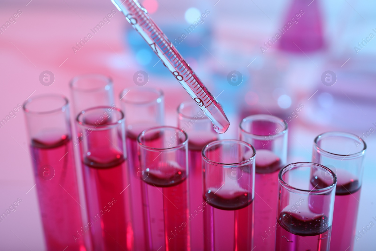 Photo of Dripping reagent into test tube with red liquid, closeup. Laboratory analysis