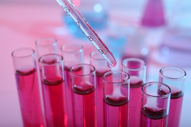 Photo of Dripping reagent into test tube with red liquid, closeup. Laboratory analysis