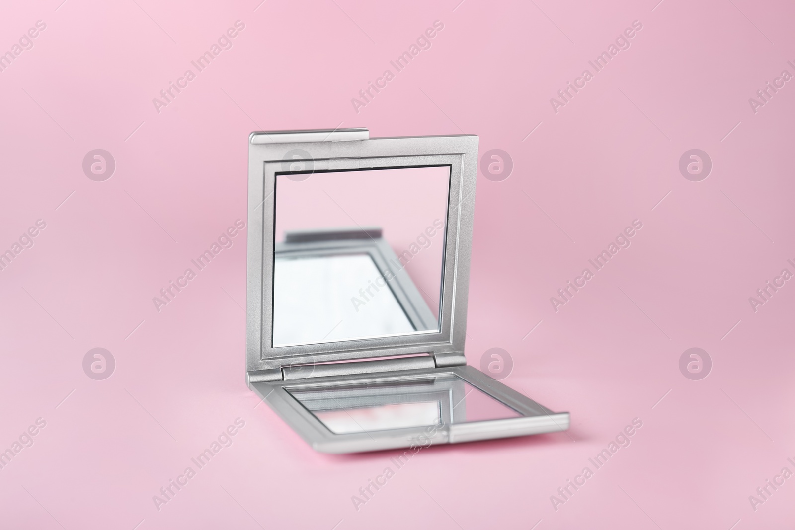 Photo of Stylish cosmetic pocket mirror on pink background