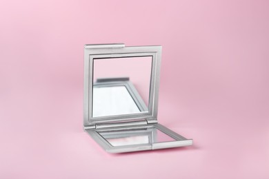 Stylish cosmetic pocket mirror on pink background