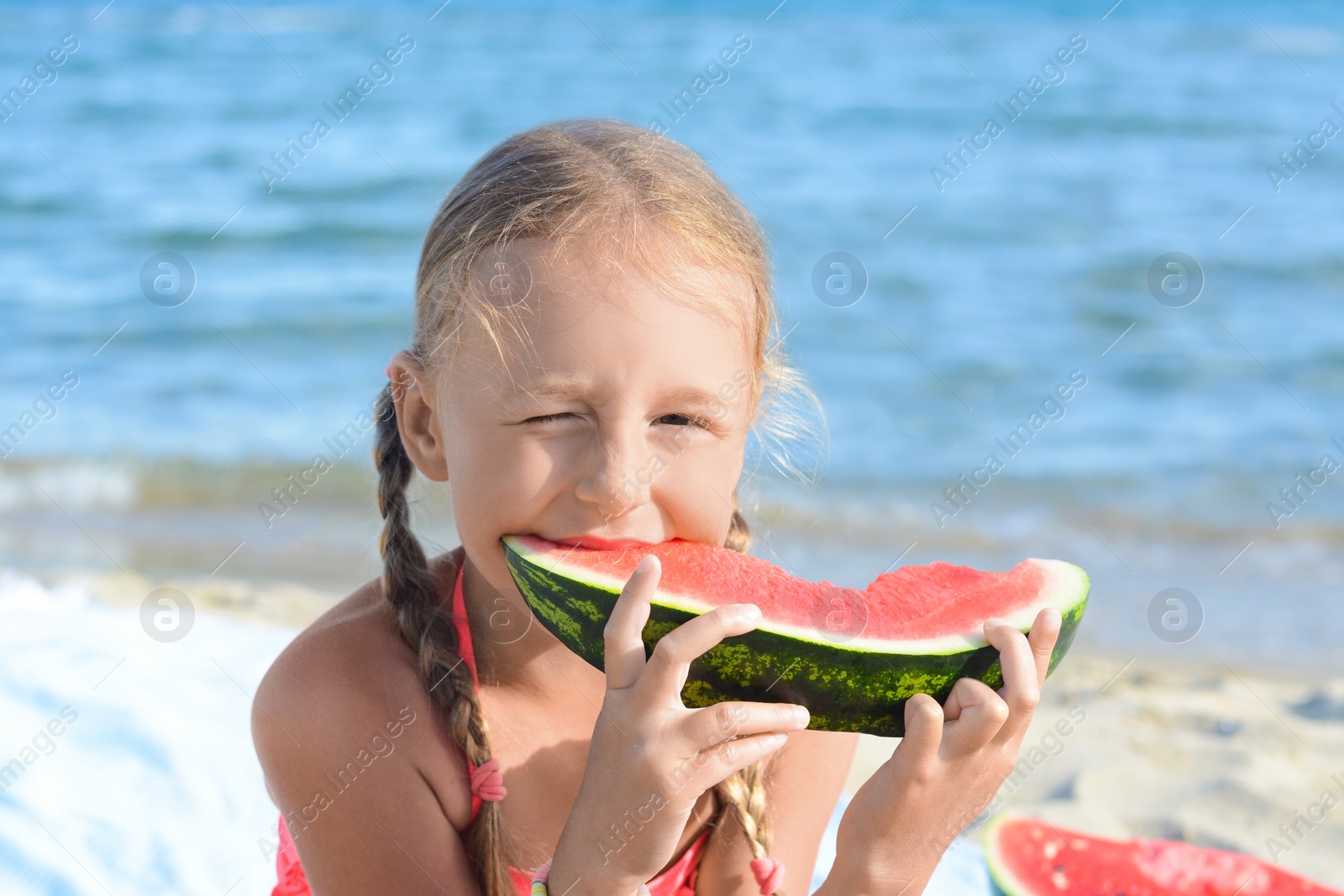 Photo of Cute little girl eating juicy watermelon on beach