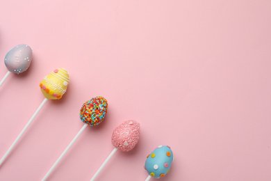 Photo of Egg shaped cake pops and space for text on pink background, flat lay. Easter celebration