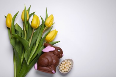 Photo of Flat lay composition with chocolate bunny and beautiful tulips on white background, space for text. Easter celebration