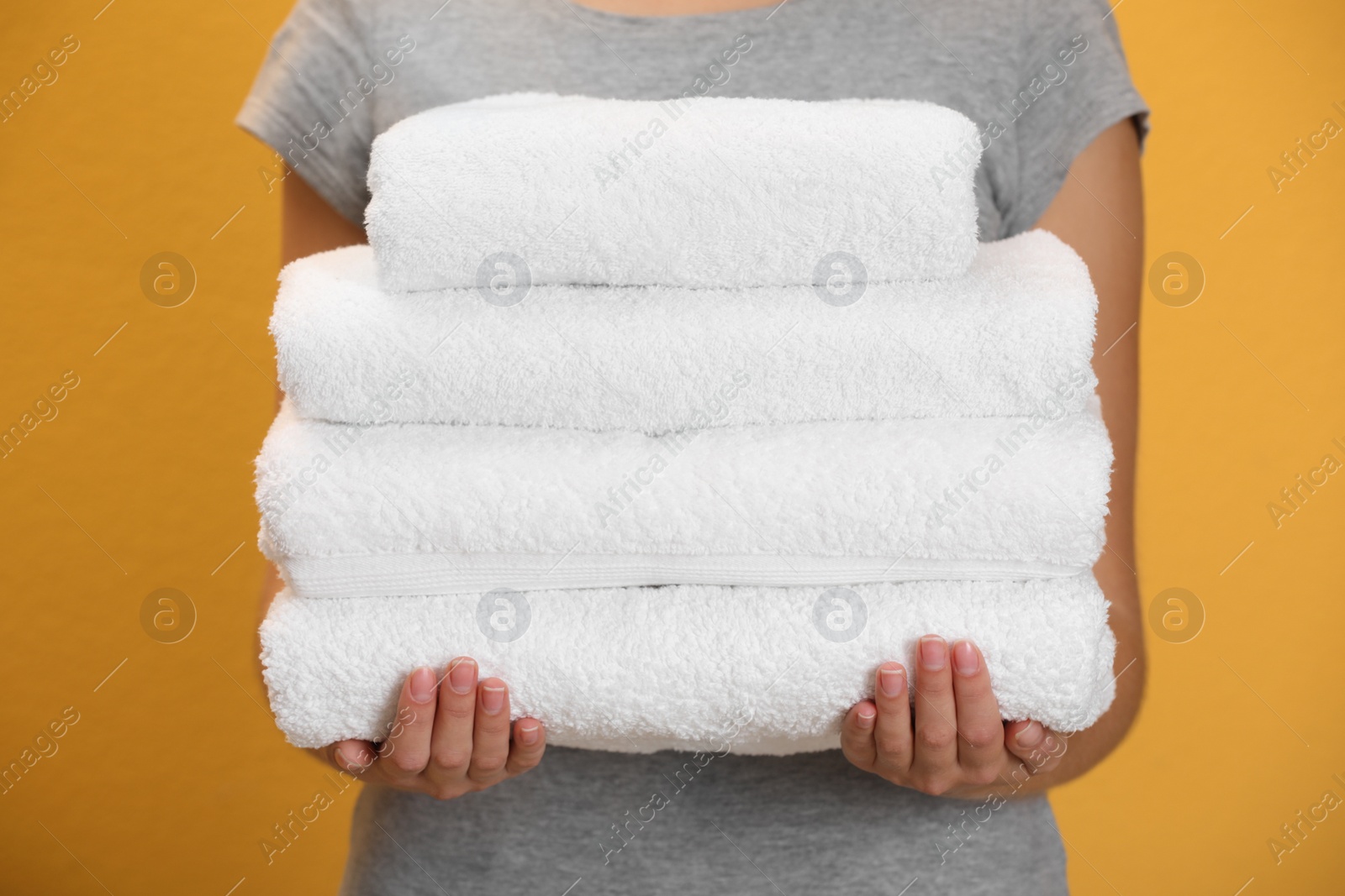 Photo of Woman holding fresh towels on orange background, closeup